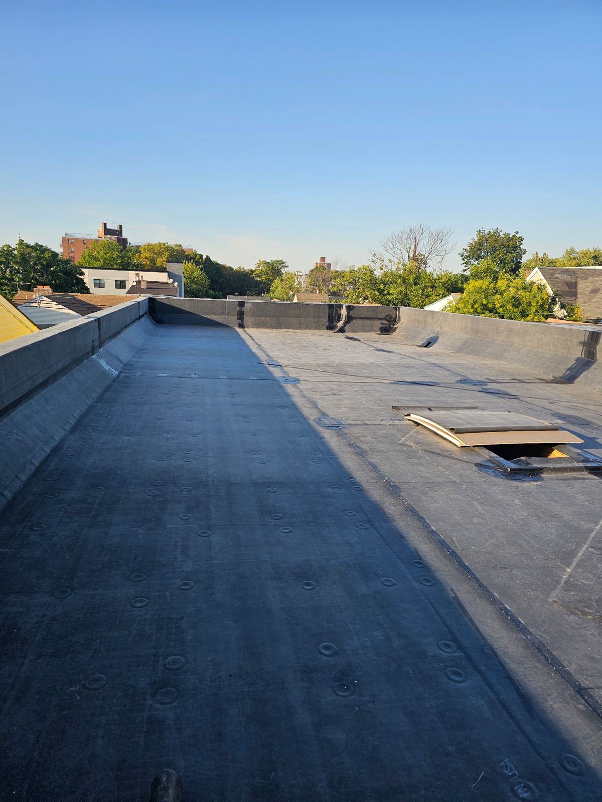 Completed EPDM flat roof running to a parapet wall