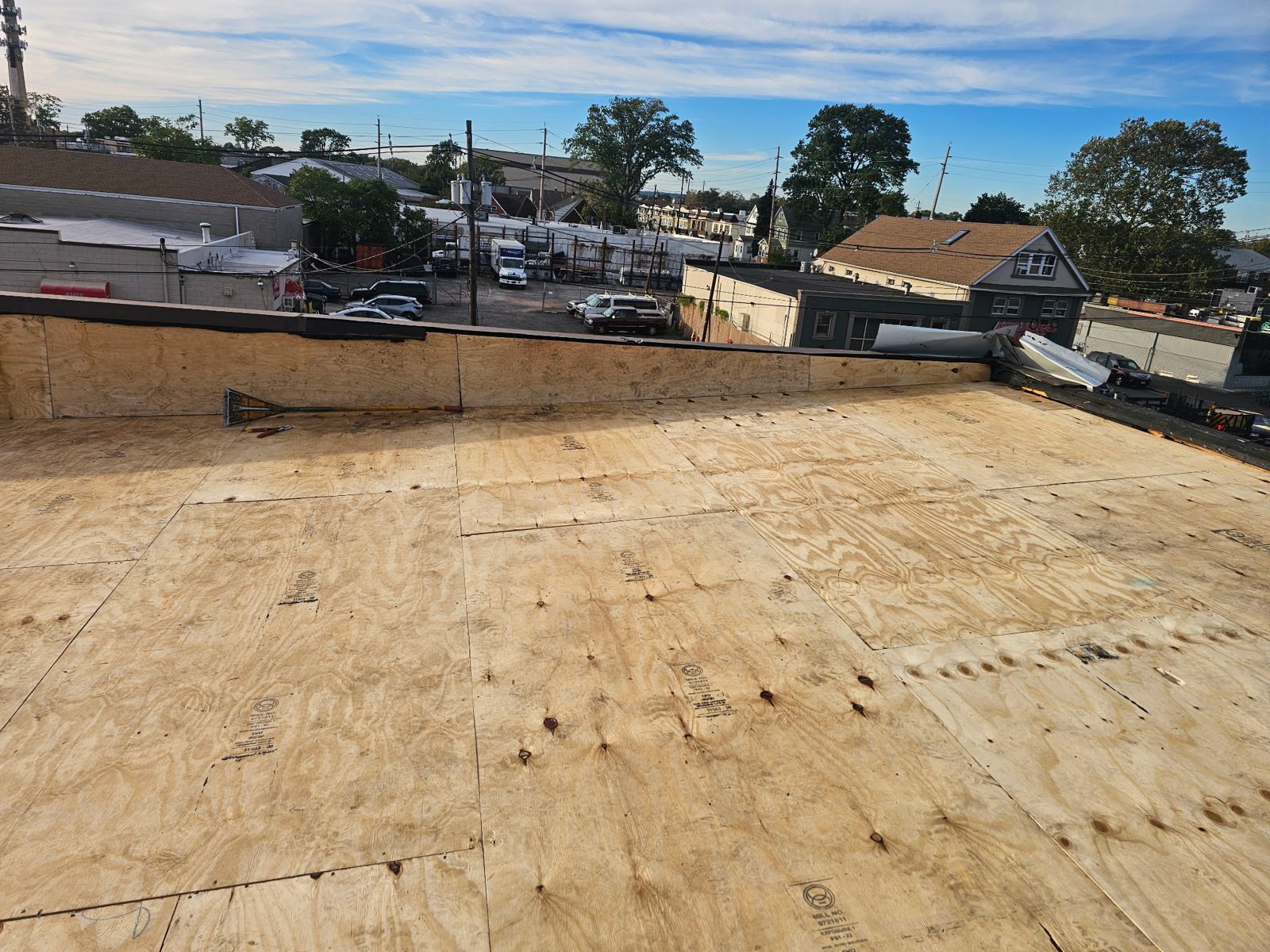 New plywood decking installed across a flat roof after tear-off